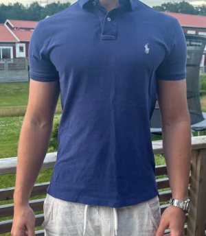 Pikétröja Ralph lauren  - Säljer en mörkblå Ralph Lauren pikétröja i storlek S, Custom Fit. Tröjan är i mycket fint skick utan hål eller fläckar. Klassisk modell med vit broderad Polo-logga på bröstet. Priset är inte hugget i sten.    