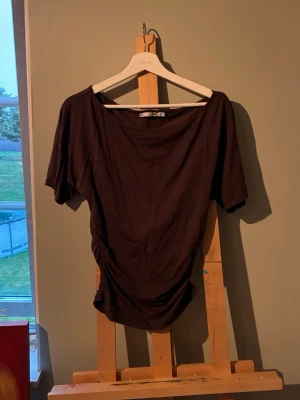 Brun topp från lager 157 med kort ärm  - Mörkbrun topp från lager 157 med korta ärmar, rynkade sidosömmar och rund halsringning. Väldigt skön och mjuk material. Tajt runt midjan och lite lös över bröstet och i armarna. Super snygg tröja, tyvärr så passa inte den mig💕🤎