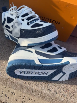 Louis Vuitton blåvita sneakers - Snygga sneakers från Louis Vuitton i blått och vitt med chunky sula och coola detaljer. Ovandelen är i en mix av läder och mesh med tydliga loggor och kontrasterande paneler. Perfekta för dig som vill sticka ut med exklusiva skor och streetwear-vibe.