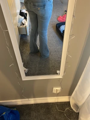 Ljusblå bootcut jeans - Säljer ett par ljusblå bootcut jeans med klassisk femficksmodell och knappgylf. Jeansen har utsvängda ben och sitter snyggt över höften. Perfekta till vardags för en avslappnad men trendig look.