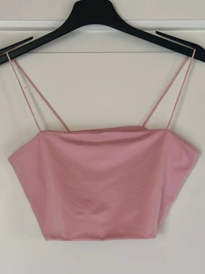 Ljusrosa bandeau topp med smala band - Söt ljusrosa bandeau topp med tunna axelband och croppad passform. Toppen har en enkel och stilren design som passar perfekt till sommaren.