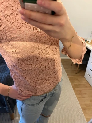 Rosa spetsblus med trekvartsärm - Söt rosa blus i spets med blommigt mönster och trekvartsärmar. Blusen har en figurnära passform och lätt utsvängda ärmslut. Perfekt för dig som gillar romantisk och feminin stil.