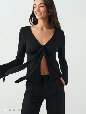 Svart långärmad topp med knyt - Trendig svart långärmad topp från Gina Tricot med v-ringning och snygg knytning framtill. Toppen har några defekter. Skriv för egna bilder💕💕