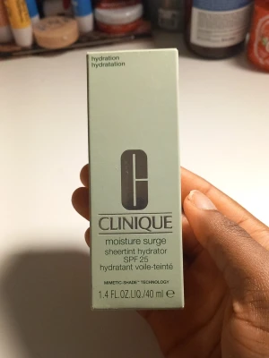 Clinique Moisture Surge Sheertint SPF 25 - Clinique Moisture Surge Sheertint Hydrator SPF 25 är en återfuktande foundation med lätt täckning. Kommer i en mintgrön kartong och innehåller 40 ml. Ger en naturlig finish och skyddar huden med SPF 25. Perfekt för dig som vill ha en fräsch och återfuktad look.