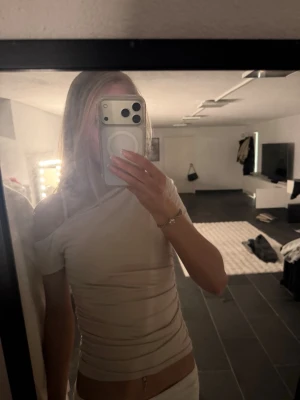 Beige oneshoulder topp - Trendig beige oneshoulder topp med tight passform och kort ärm. Snygg asymmetrisk design som ger en modern look. Perfekt att styla med både jeans och kjol.