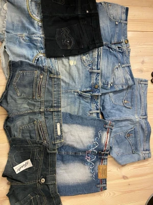Mix av jeansshorts i olika tvättar - Säljer ett gäng snygga jeansshorts i olika blå och svarta nyanser. Flera har slitningar, dragkedjedetaljer och broderier. Perfekta för sommaren och passar till allt. Materialet är klassisk denim och vissa har coola detaljer som broderi och slitna kanter.!ALLA SÄLJS FÖR SIG! PRIS KAN DISKUTERAS!