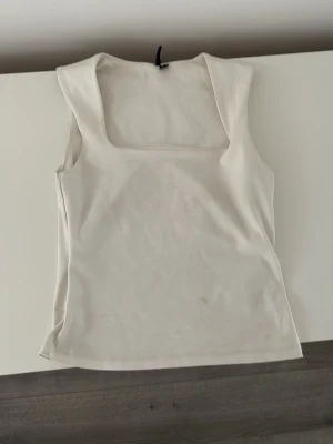 Vit linnetopp från Vero Moda - Säljer en stilren vit linnetopp från Vero Moda med breda axelband och fyrkantig ringning. Toppen är ärmlös och har en enkel, clean look som passar till allt. Perfekt att matcha med jeans eller kjol för en fräsch outfit.