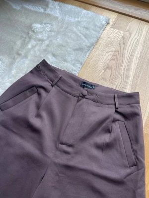 Bruna vida kostymbyxor - Ett par bruna kostymbyxor med hög midja och vida ben. Har sytt upp de för att passa mig som är 170. 