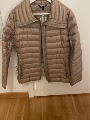 Beige pufferjacka från Ralph Lauren - Snygg beige pufferjacka från Ralph Lauren med hög krage och två dragkedjeförsedda fickor.  Perfekt för våren, säljer pga den är lite för stor för mig i armarna(storlek S) Jag är 160cm. Nypris 2000🥰