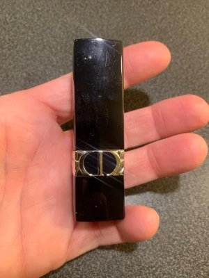 Dior läppstift i kall rödbrun nyans, nr 964 - Snyggt läppstift från Dior med elegant svart hylsa och silverdetalj. Färgen är en kall rödbrun ton som ger ett naturligt och stilrent resultat. Hylsan är klassiskt formad och känns lyxig i handen. Perfekt för dig som vill ha en exklusiv look.