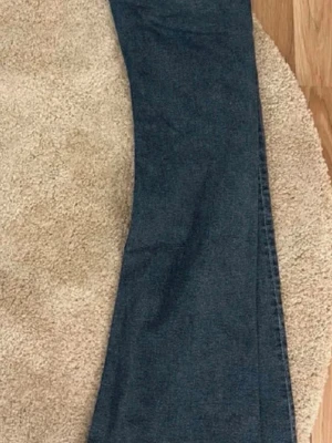 Blå bootcut jeans med utsvängda ben - Säljer ett par klassiska blå bootcut jeans med snyggt utsvängda ben. Jeansen har en tvättad look med ljusare partier framtill och är tillverkade i denim. Perfekta för dig som gillar retrostil och vill ha ett par jeans som sticker ut.