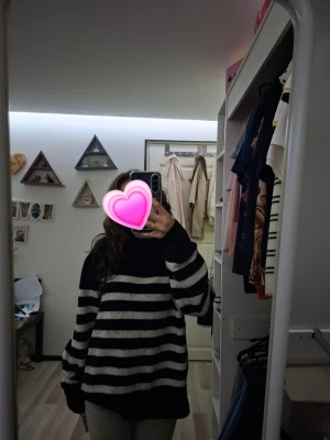 Svartvit randig stickad tröja - Säljer en mysig stickad tröja med svarta och vita ränder. Tröjan har avslappnad passform, långa ärmar och rund halsringning. Perfekt för dig som gillar en chill och stilren look. Passar till jeans för en fin enkel outfit.