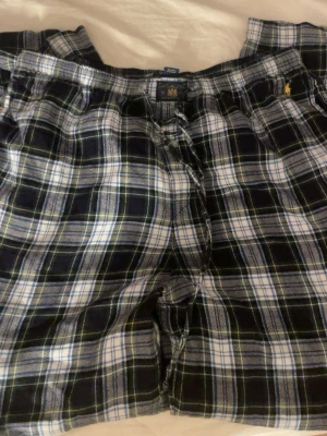 Rutiga pyjamasbyxor Polo Ralph Lauren - Mysiga pyjamasbyxor från Polo Ralph Lauren i svart, vitt och blått rutigt mönster. Byxorna har dragsko i midjan och är tillverkade i mjuk bomull. Perfekta för chillkvällar hemma.