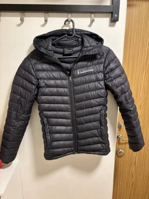Dun jacka från peak performance  - Snygg svart pufferjacka från peak performance med huva och dragkedja framtill. Jackan har två sidofickor med dragkedja och quiltad design som ger en sportig look.  Kan lösa fler bilder om så önskas ☺️