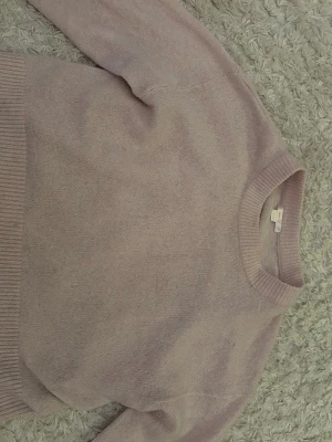 Ljusrosa stickad tröja Gina Tricot - Mysig ljusrosa stickad tröja från Gina Tricot med rund halsringning och ribbade muddar vid ärmslut och nederkant. Perfekt för lager på lager och enkel att matcha med jeans eller kjol.