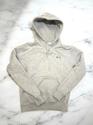 Grå hoodie från Ami Paris - Snygg ljusgrå hoodie från Ami Paris med liten broderad logga på bröstet.                                   Nypris 3100kr Mycket bra skick Bra kvalité +väldigt skön . Helängd 61cm Bredd 46 cm Armlängd 58cm