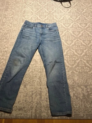 Ljusblå raka jeans - Säljer ett par ljusblå jeans med rak passform och klassisk femficksdesign. Jeansen har bälteshällor och stängs med knapp och dragkedja. Perfekta för en avslappnad och stilren look. Materialet är denim i bomull.