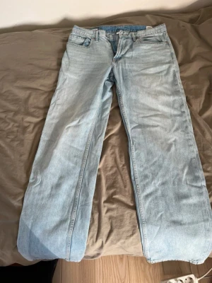Ljusblå baggy jeans - Säljer ett par ljusblå jeans med rak passform och klassisk femficksdesign. Jeansen har normal midja och är tillverkade i denim. Perfekta för en avslappnad och trendig look.