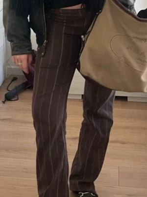 lågmidjade kostymbyxor  - bruna kostymbyxor med vita kritstrecksränder🤎🤍 mjukt material och bra skick, modellen är 167cm lång