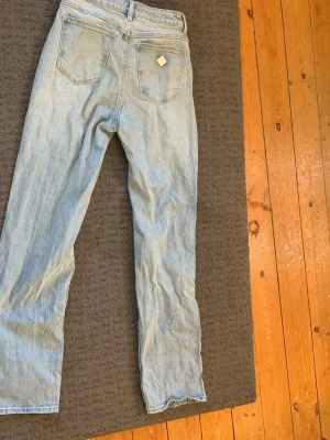Ljusblå raka jeans - Säljer ett par ljusblå jeans med rak passform och klassiska bakfickor. Jeansen har hög midja och är tillverkade i ett slitstarkt denimtyg. Perfekta för en avslappnad och trendig look.