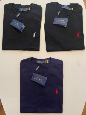 3-pack  t-shirt Polo Ralph Lauren - Klassiska t-shirts från Polo Ralph Lauren med rund hals och korta ärmar. Ikoniska broderade loggan i rött på bröstet. Tillverkad i mjuk bomull för en skön och stilren look. Perfekt till jeans eller shorts.