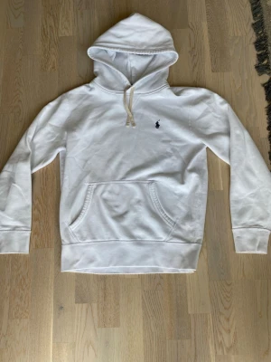 Vit hoodie från Polo Ralph Lauren - Snygg vit hoodie från Polo Ralph Lauren med klassisk huva och dragsnöre. Tillverkad i mjukt bomullsmaterial. Storlek S