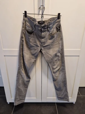 Grå raka jeans från Replay  storlek 31x34 - Säljer ett par grå jeans från med rak passform och klassisk femficksdesign. Jeansen har bälteshällor, dragkedjegylf och är tillverkade i ett mjukt denimtyg. Perfekta för en avslappnad och stilren look.