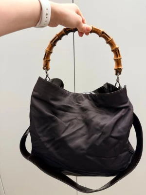 Gucci väska med handtag i kassisk Gucci bambu  - En jättefin Gucci väska säljs. Väskan är i mycket fint skick, med axelrem, i brun färg. Original dustbag medföljer. 