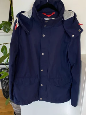 Vårjacka med avtagbar luva! - Snygg blå vårjacka med huva. 2 st innefickor. Jackans fickor har magnetknäppe. Huvan är avtagbar. Nyskick på jacka, knappt använd!  Väldigt likt en Lanvin jacka.  Priset går självklart att diskutera! 