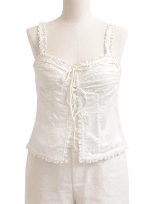 Vit linnetopp med snörning - Supersöt vit linnetopp med snörning framtill och dekorativa spetsdetaljer längs kanterna. Toppen har smala axelband och en lätt croppad passform som ger en romantisk vibe. Perfekt att styla med jeans eller kjol för en trendig look.