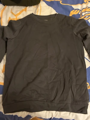 Mörkgrå sweatshirt från Primark - En enkel och stilren mörkgrå sweatshirt från Primark. Tröjan har rund halsringning, långa ärmar och ribbade muddar vid ärmslut och nederkant. Perfekt för en avslappnad look och lätt att matcha med andra plagg.