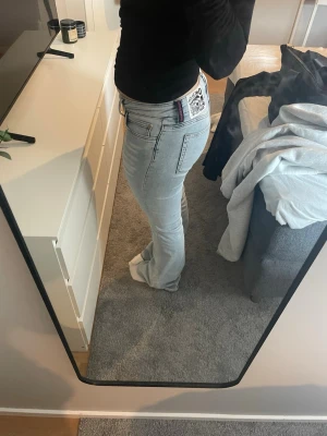 Ljusblå bootcut jeans från Weekday - Säljer ett par ljusblå bootcut jeans från Weekday med klassisk femficksmodell och cool patch på bakfickan. Jeansen har en något utsvängd passform och detaljerade sömmar. Perfekta för dig som gillar en avslappnad men trendig stil.