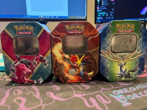 Pokémon samlarburkar i plåt - Tre färgglada samlarburkar i plåt från Pokémon Trading Card Game med motiv av Yveltal, Delphox och Xerneas. Burkarna har fönster på framsidan och är perfekta för att förvara kort eller småprylar. Snygg design med röd, blå och grön färg samt detaljerade illustrationer.