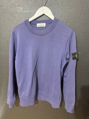 sweatshirt från Stone Island - Snygg sweatshirt från Stone Island med klassisk rund hals och ikonisk logotyp-patch på vänster ärm. Tröjan har ribbade muddar vid ärmslut och nederkant. Perfekt för en avslappnad och trendig stil.