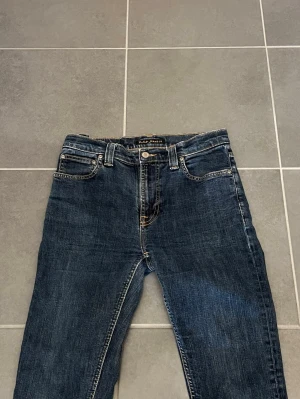 Mörkblå Nudie Jeans - Klassiska Nudie jeans för män, Storlek W30/L32. Nyskick, inga skador/slitage. Väldigt bekväm och snygg passform. Hör av dig vid intresse/frågor. PRIS KAN DISKUTERAS!
