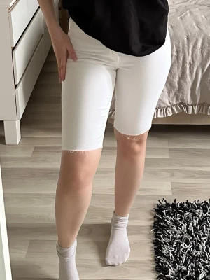 Vita jeansshorts med rå kant - Snygga vita jeansshorts med rå, fransad kant nertill. Perfekta för sommaren och lätta att matcha med olika toppar. Stretchigt material 