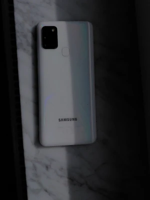 Vit Samsung Galaxy Android-telefon - Snygg vit Samsung Galaxy med stilren design och rundade hörn. Baksidan är i blankt plastmaterial och har fingeravtrycksläsare samt fyrkantig kameramodul. Framsidan har stor skärm med tunna kanter.