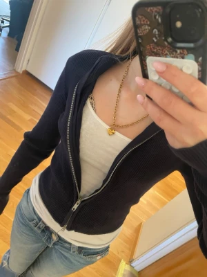 Brandy Melville Mörkblå ribbad ziptröja - Snygg mörkblå ribbad ziptröja med lång ärm och dragkedja framtill från brandy Melville. Tröjan har en tight passform och är perfekt att bära över ett linne eller t-shirt. Enkel och stilren design som passar till jeans eller kjol.