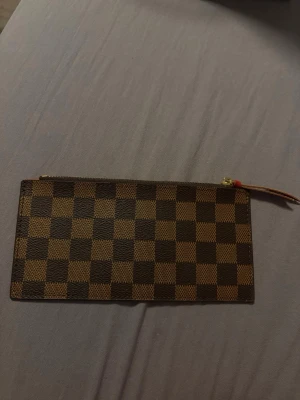 Plånbok -  Plånboken har dragkedja med gulddetalj och röd insida. Tillverkad i canvas med läderdetaljer och passar perfekt för kort och kontanter.