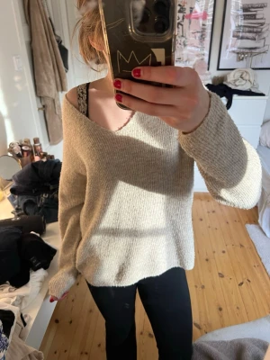 Beige stickad tröja V-ringad Vero Moda - Mysig beige stickad tröja från Vero Moda med V-ringning och långa ärmar. Tröjan har en avslappnad passform och är tillverkad i ett mjukt, ribbstickat material. Perfekt för lager-på-lager och chill dagar.