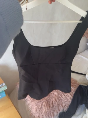 Svart figurnära topp - Snygg svart linnetopp med breda axelband och fyrkantig urringning. Toppen är figurnära och har en stilren, enkel design 