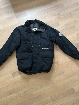 Svart jacka Peak Performance stl 160 - En svart fodrad jacka som passar bra som tex skidjacka. Fodrad.  En diffus fläck som syns inringad på andra bilden  Snölås längst ner så att man kan dra åt.  Storlek 160