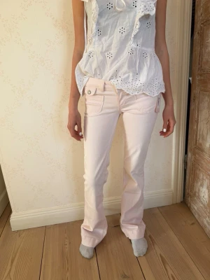 Ljusrosa bootcut jeans  - Säljer ett par ljusrosa jeans från Nelly med bootcut-modell och låg midja. Jeansen har klassiska fem fickor, bälteshällor och knappgylf. GAAALET snygga!!🩷💝 Nypris 600 kr