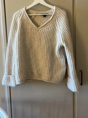 Beige stickad tröja med v-ringning - Mysig beige stickad tröja från NewYorker med v-ringad hals. Tröjan har en avslappnad passform och är tillverkad i ett tjockare garn som ger en varm känsla. Perfekt för kyliga dagar och enkel att matcha till olika outfits. Aldrig använt!💕