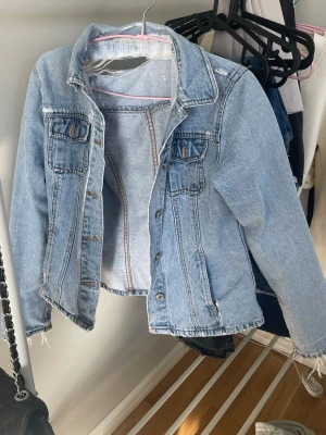 Jeansjacka - En blå sliten jeansjacka. Hål i ryggen som var när jag köpte den (begagnat). Tycker slitningarna bidrar till stilen.