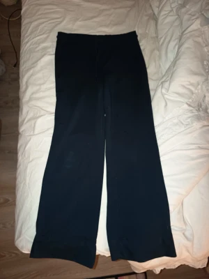 Mörk blå vida mjukisbyxor med dragsko - Mörk blå mjukisbyxor med breda ben och dragsko i midjan. Byxorna har en enkel och stilren design, perfekta för en avslappnad look. Tillverkade i mjukt och bekvämt material som passar för chill dagar hemma eller när du vill vara extra comfy.