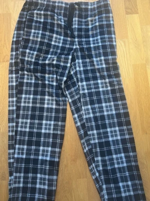 Rutiga pyjamasbyxor i blått och vitt - Mysiga pyjamasbyxor med svartvitt rutmönster och resår i midjan. Perfekta för chillkvällar hemma. Mjukt material som känns skönt mot huden och avslappnad passform. Klassisk look med dragsko i midjan.