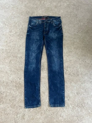 Mörkblå raka jeans från Pull&Bear - Snygga mörkblå jeans från Pull&Bear med raka ben och klassisk femficksmodell. Jeansen har slitna detaljer och kontrastsömmar samt en läderpatch bak i midjan. Perfekta för en avslappnad och trendig look.