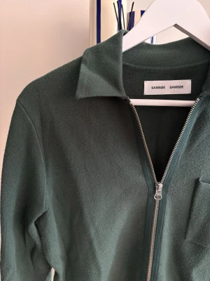 Grön ziptröja från Samsøe Samsøe S - Mörkgrön långärmad ziptröja från Samsøe Samsøe med klassisk krage och bröstficka. Finns även i mörkblå på min profil!