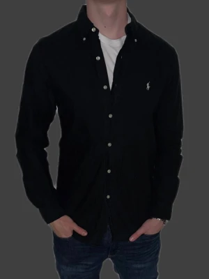 Svart skjorta från Ralph Lauren - Svart skjorta från Ralph Lauren i storlek M.  Fint skick till ett bra pris. Nypris: 1995kr. Mitt pris: 349kr. Vid frågor eller funderingar, tveka inte att höra av dig.